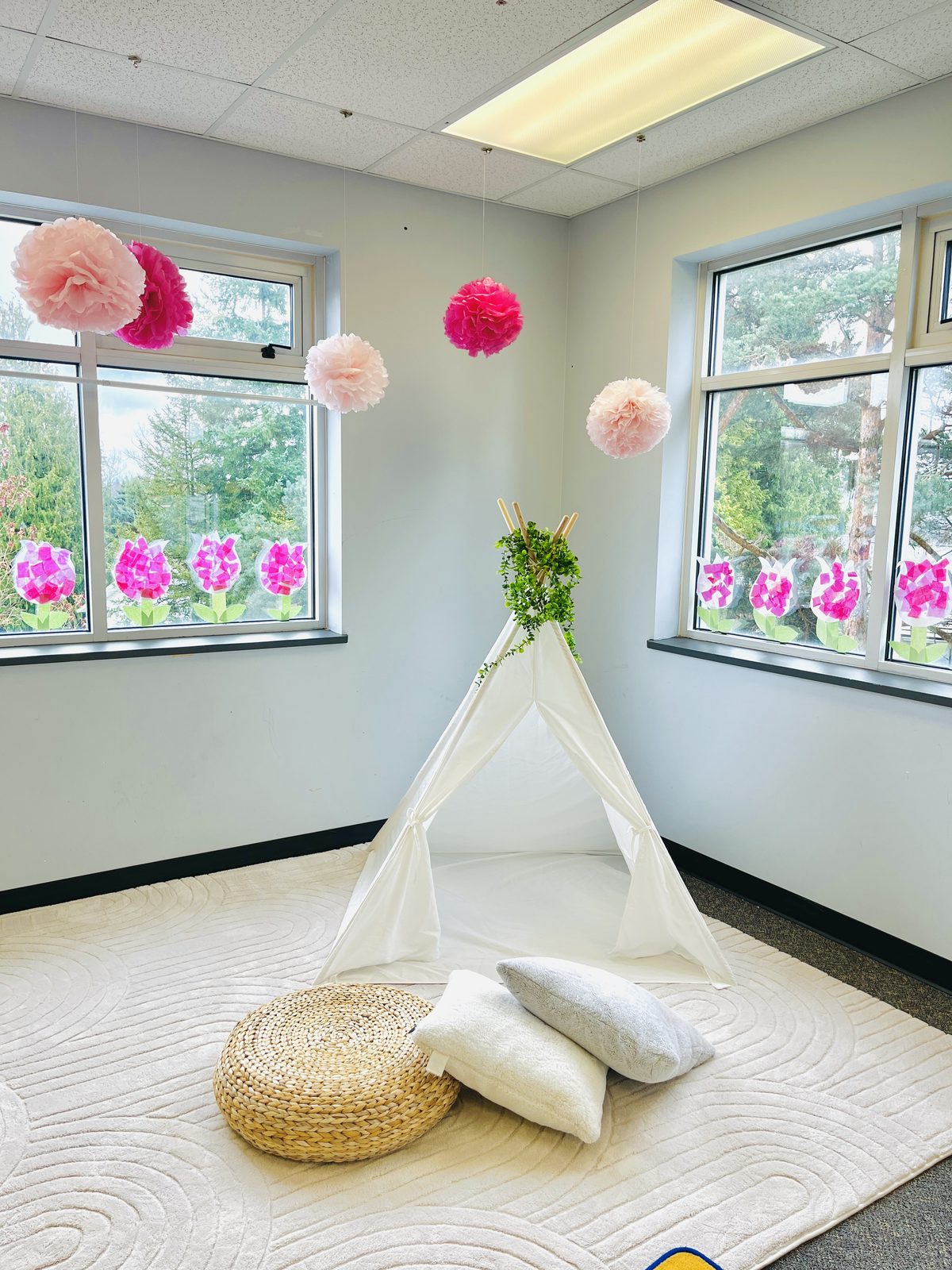 A cozy reading nook with a teepee, floor cushions, and paper flower decorations in a Bright Steps classroom