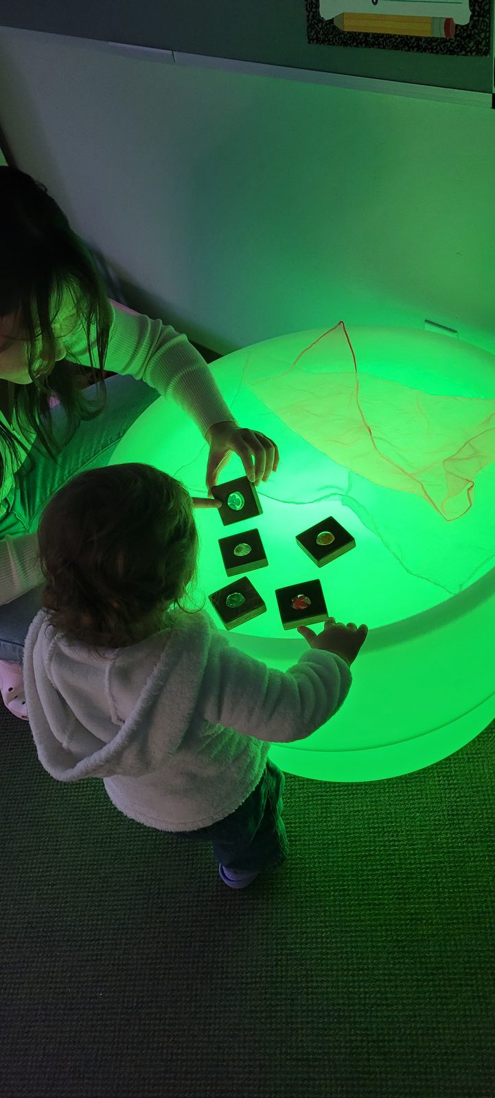 Toddlers exploring translucent shapes on a glowing light table