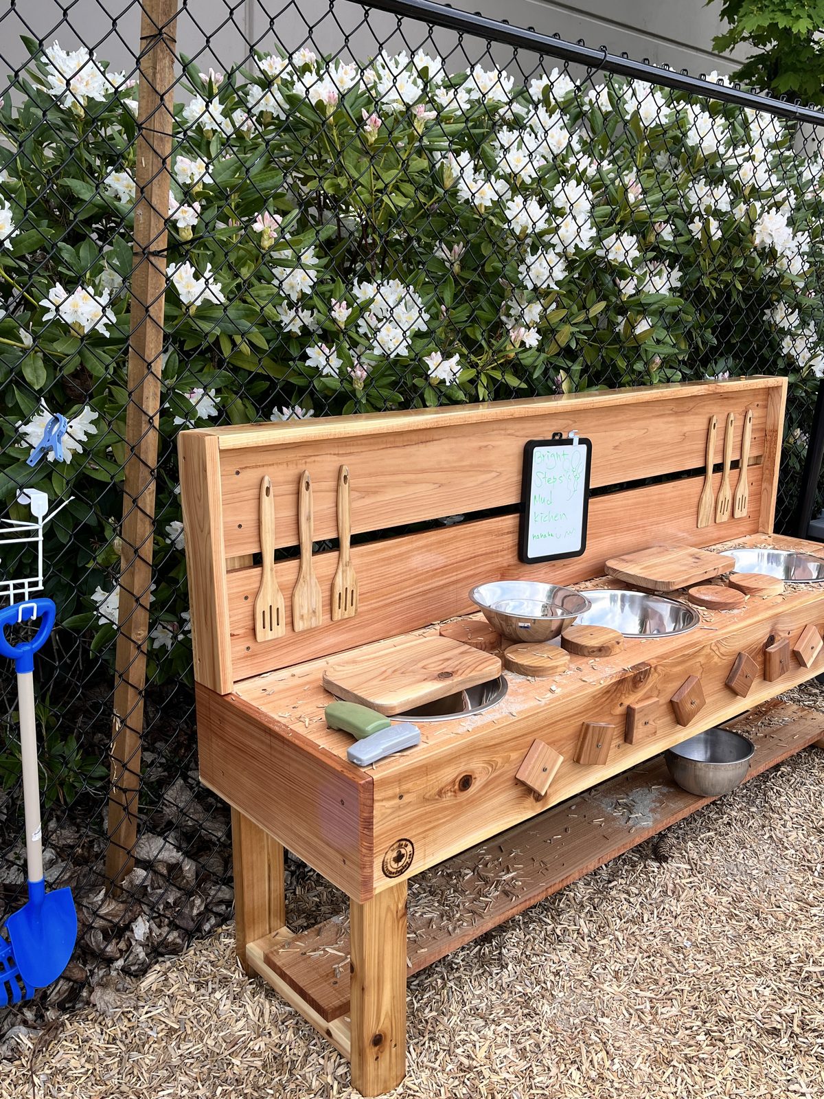 The Bright Steps outdoor mud kitchen with wooden utensils and mixing bowls