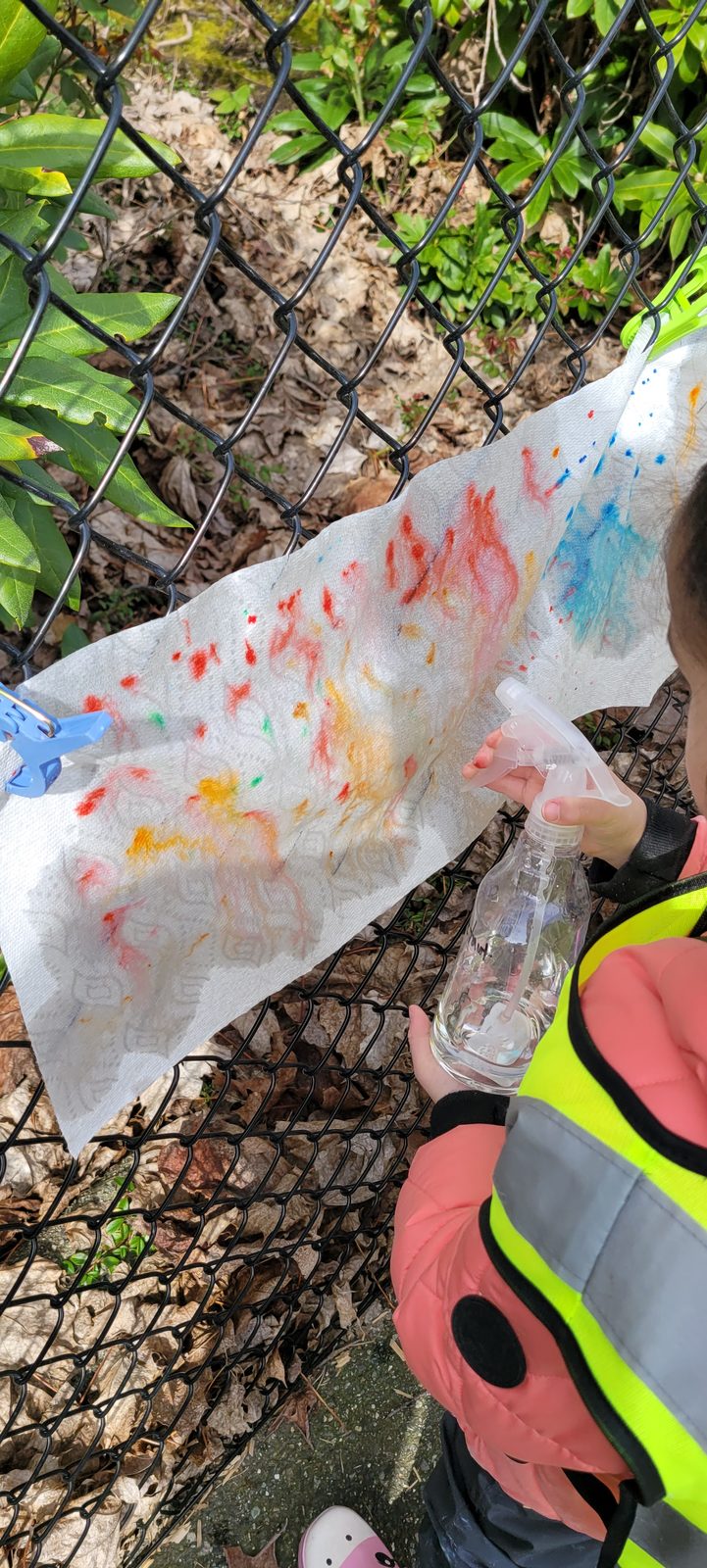 A child spraying water to make marker colours bleed across paper towel